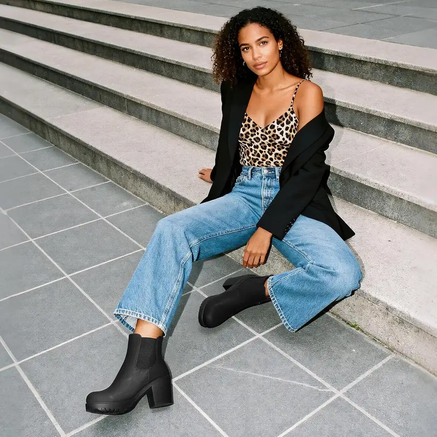 woman wearing black chelsea ankle boots with light jeans and a blazer