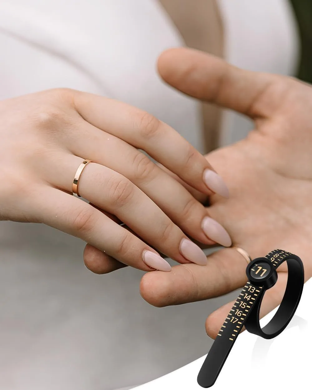 hands wearing a ring next to a black ring sizer tool with magnifier