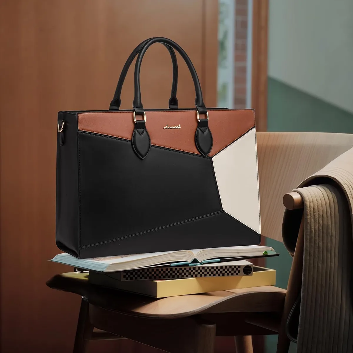 color block laptop tote bag standing on a chair beside books