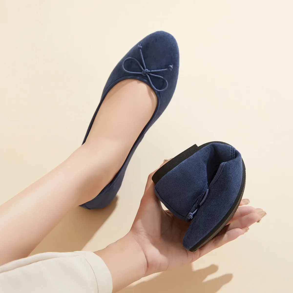 navy soft microsuede ballet flat folded in one hand to show the flexible sole