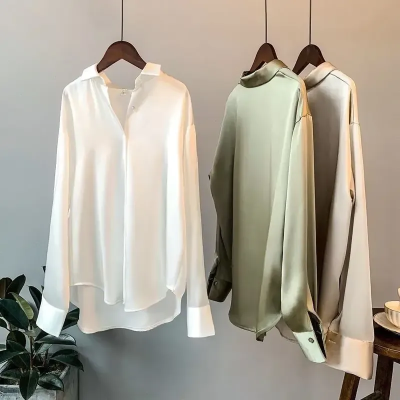 curved high-low hem and deep cuffs of the white satin shirt
