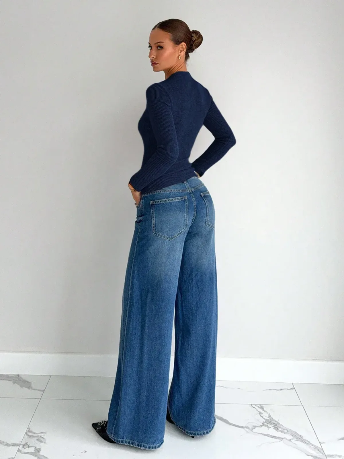 navy blue twist front rib knit top worn with wide leg jeans, side view