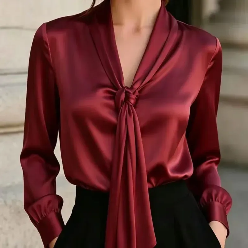 knotted scarf tie at the V neck of the burgundy satin blouse